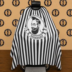 Professional barber cape with a custom logo printing area displayed on a barber chair.